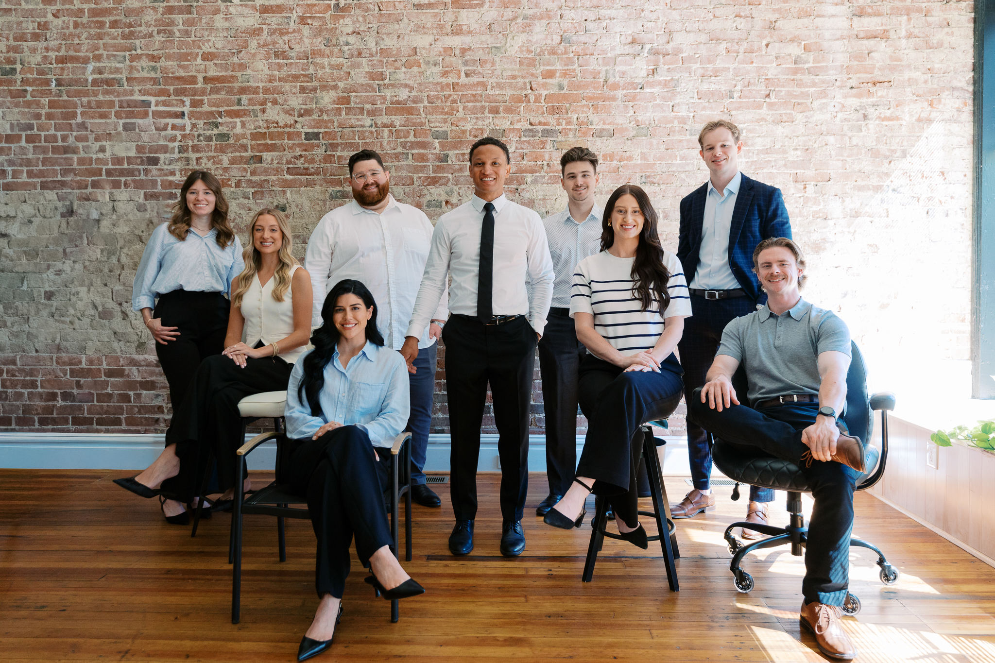 Wide shot of the full Posted Social team in business attire in the brick-walled St. Louis studio