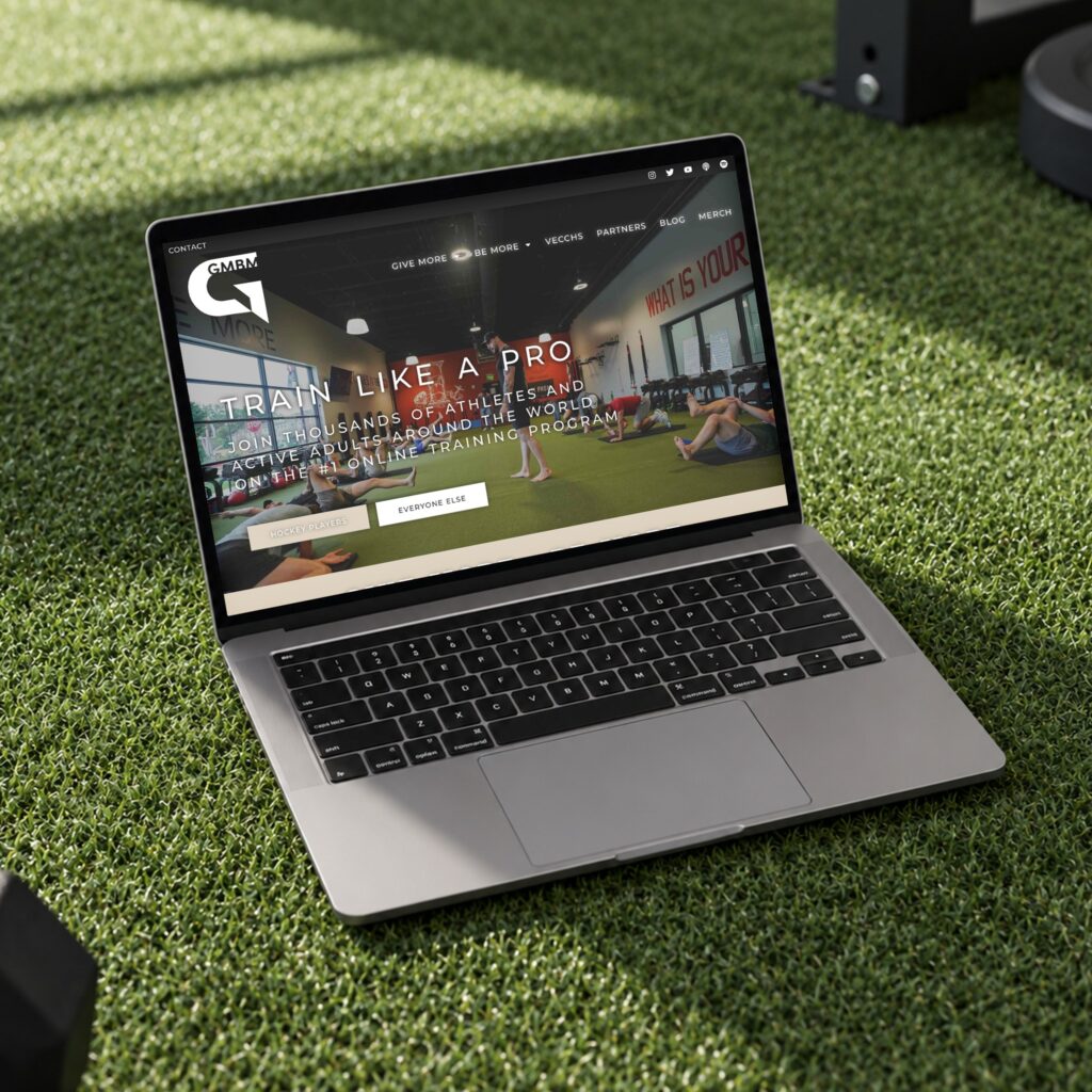 Laptop mockup of the GMBM sports training website homepage on a turf field, designed by Posted Social