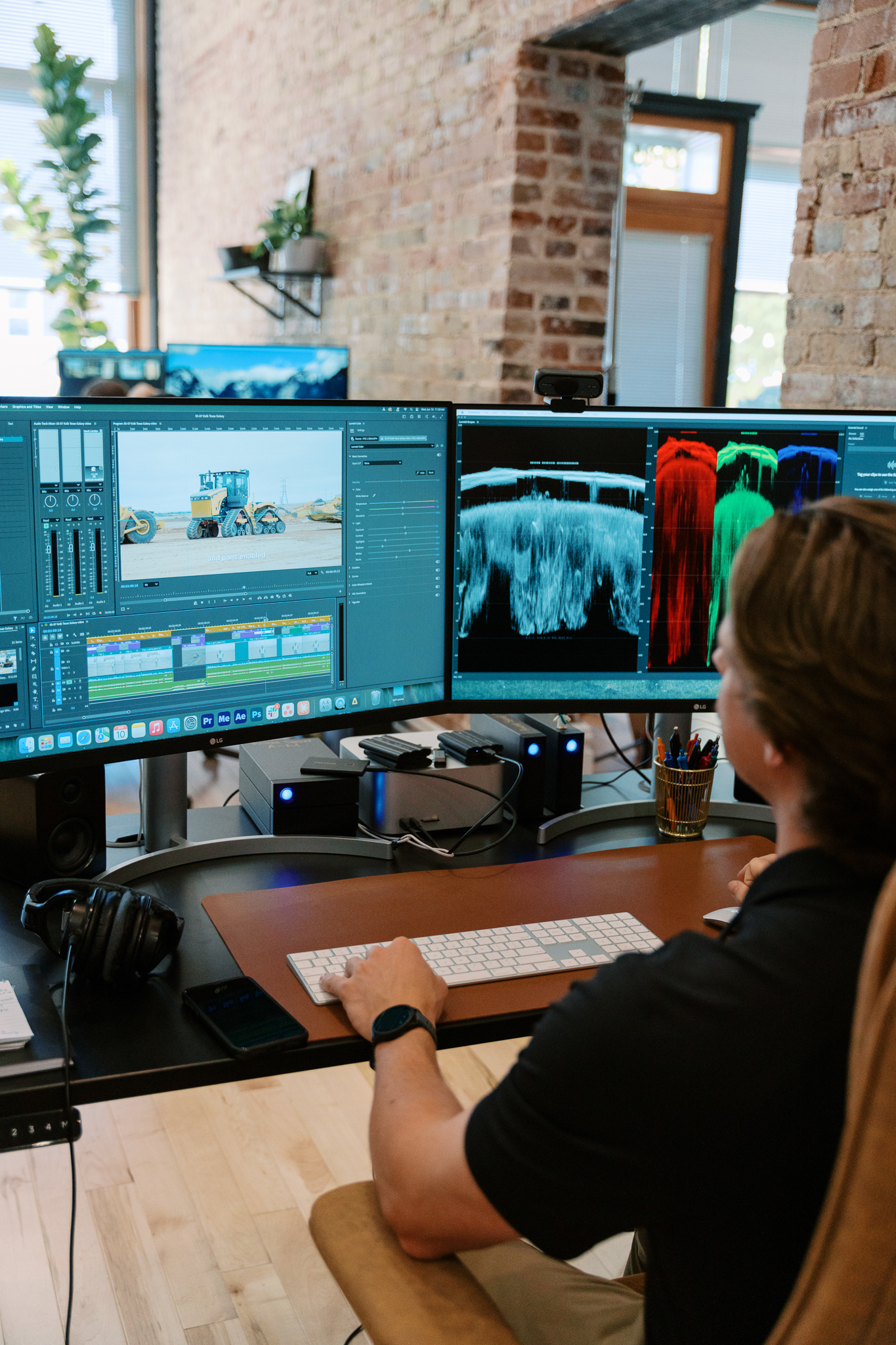 Video editor working in a timeline-based editing suite on dual monitors